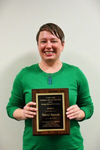 Valerie Bartush holding the plaque for the V. Ann Lewis Academic Advisor of the Year Award for 2024