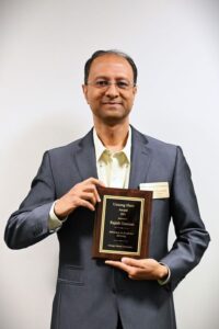 Dr. Rajesh Ganesan holding the plaque for the Unsung Hero Award for 2024