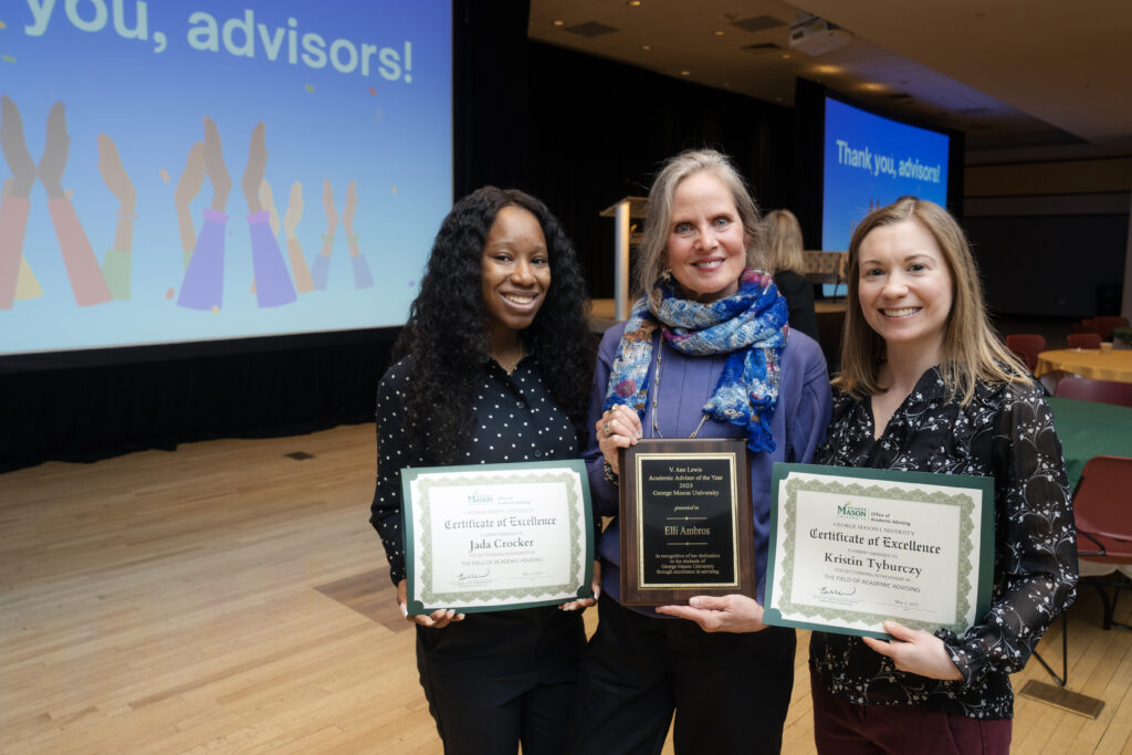 Jada Crocker, Elli Ambros, and Kristin Tyburczy stand with their certificates and plaque in front of the screens that say "Thank you, Advisors!". photo by Creative Services