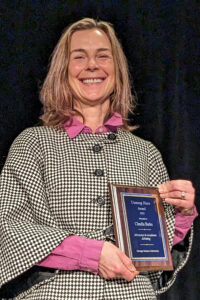 Claudia Borke holding the award for Unsung Hero