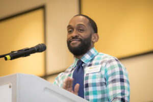 Antonio Stewart standing at the podium presenting an award. John Boal Photography