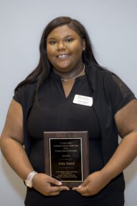 Asha Sneed holding the plaque for the V. Ann Lewis Academic Advisor of the Year Award for 2025
