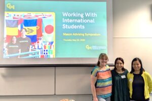 Kara Haslbeck, Veronica Bonilla, and Yali Pan stand with their title slide projected above and behind them. 